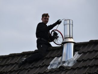 man in black jacket sitting on roof during daytime
