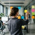 Product Owner ordnet Anforderungen als Klebezettel an einer Glaswand im Büro