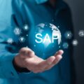 Person hält eine leuchtende Weltkugel mit dem Schriftzug SAP und Technologie-Symbolen in der Hand