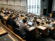 Studierende arbeiten in einem Hörsaal an Laptops